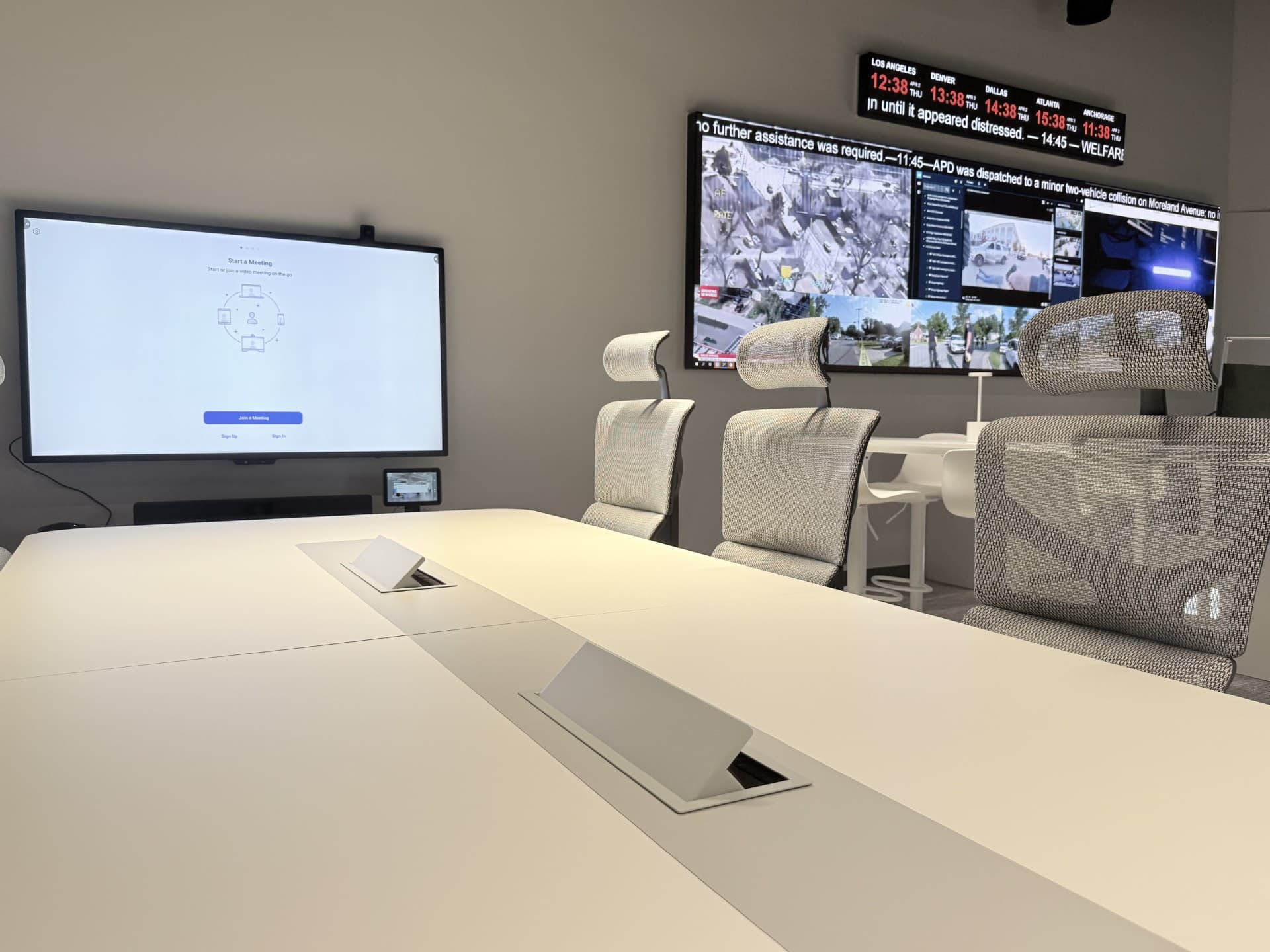 Emergency operations briefing room with a conference table and multi-screen video wall of live incident feeds